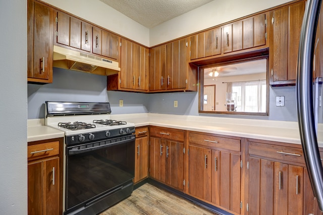 kitchen featuring stainless steel fridge, a textured ceiling, ceiling fan, black gas range, and light hardwood / wood-style floors