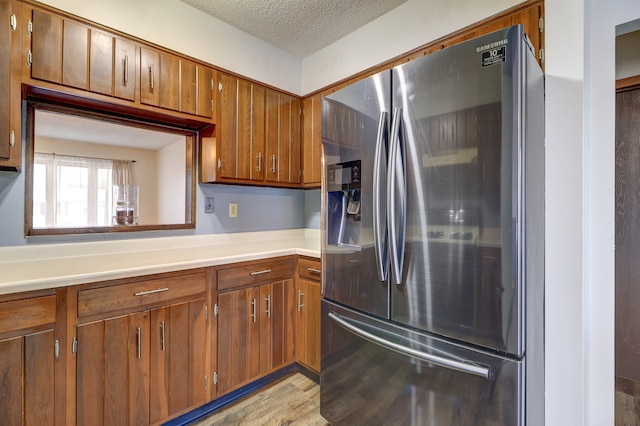 kitchen featuring stainless steel refrigerator with ice dispenser, a textured ceiling, and light hardwood / wood-style floors