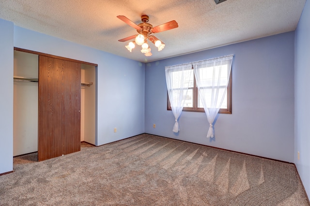 unfurnished bedroom featuring carpet, ceiling fan, a textured ceiling, and a closet