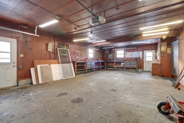 garage featuring a workshop area, wooden walls, and a garage door opener