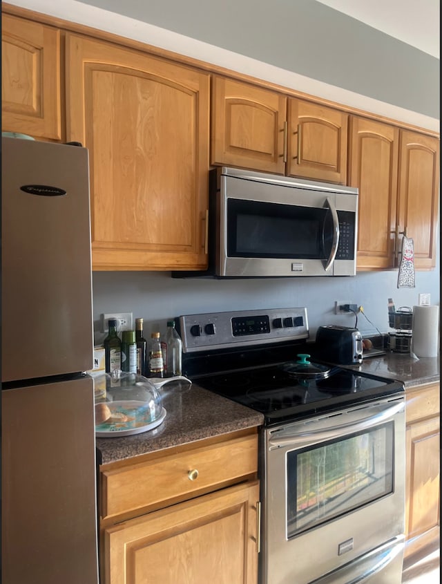 kitchen with dark stone countertops and appliances with stainless steel finishes