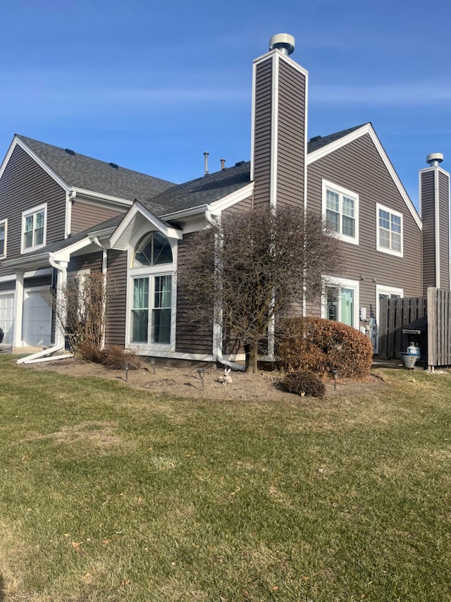 rear view of property featuring a garage and a yard