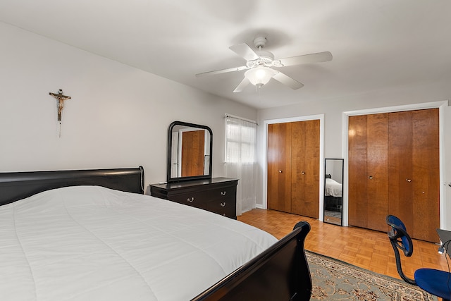 bedroom with multiple closets, ceiling fan, and light parquet floors