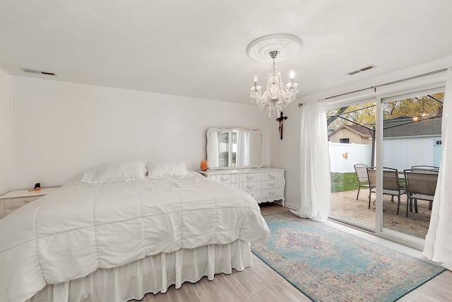 bedroom featuring an inviting chandelier, access to outside, and light hardwood / wood-style flooring