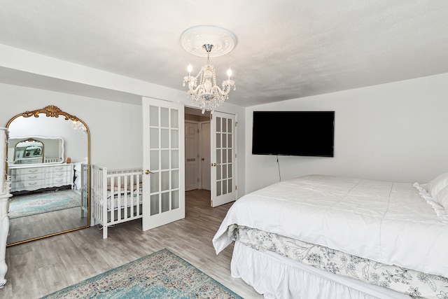 bedroom featuring hardwood / wood-style floors, a notable chandelier, and french doors