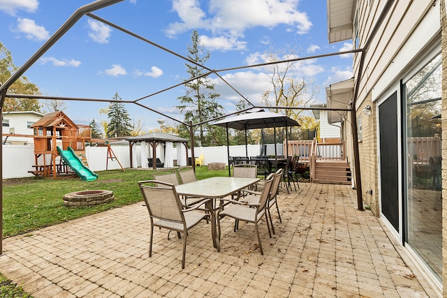 view of patio featuring a gazebo, a playground, and a fire pit