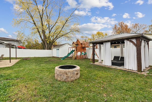 view of yard featuring a gazebo, a playground, and an outdoor fire pit