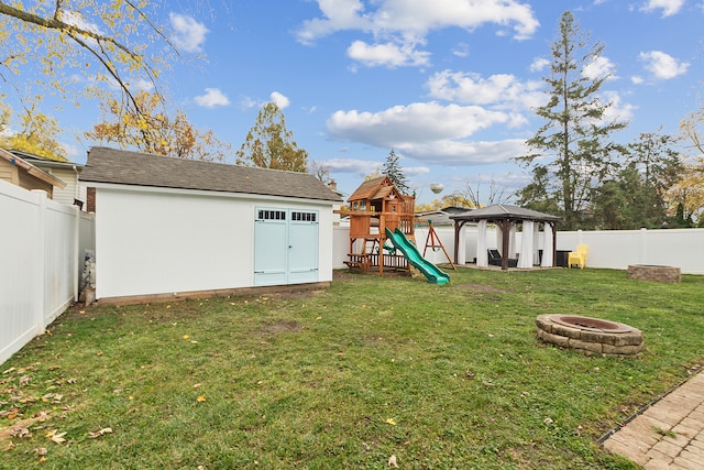 view of yard featuring a gazebo, a playground, and a fire pit