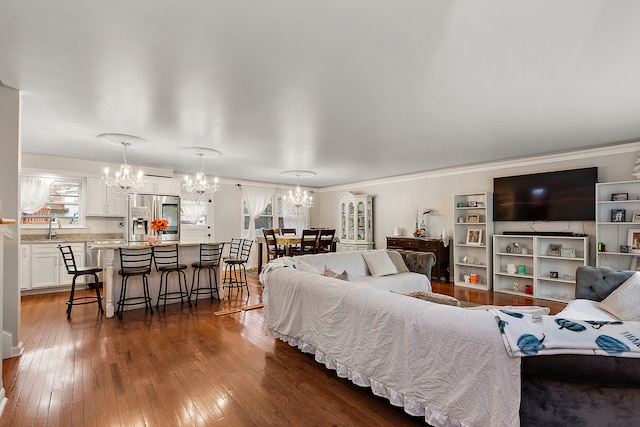 living room featuring dark hardwood / wood-style flooring, crown molding, a wealth of natural light, and a chandelier