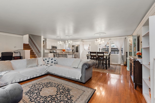 living room with wood-type flooring, crown molding, and an inviting chandelier