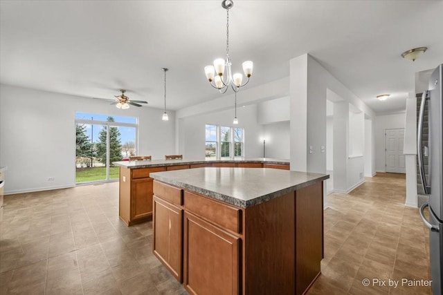 kitchen featuring a center island, stainless steel refrigerator, hanging light fixtures, and a healthy amount of sunlight