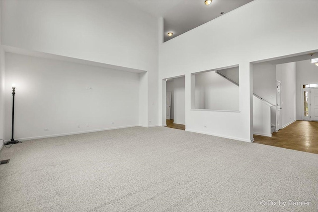 unfurnished living room featuring carpet and high vaulted ceiling