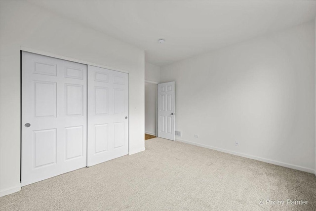 unfurnished bedroom with light carpet and a closet