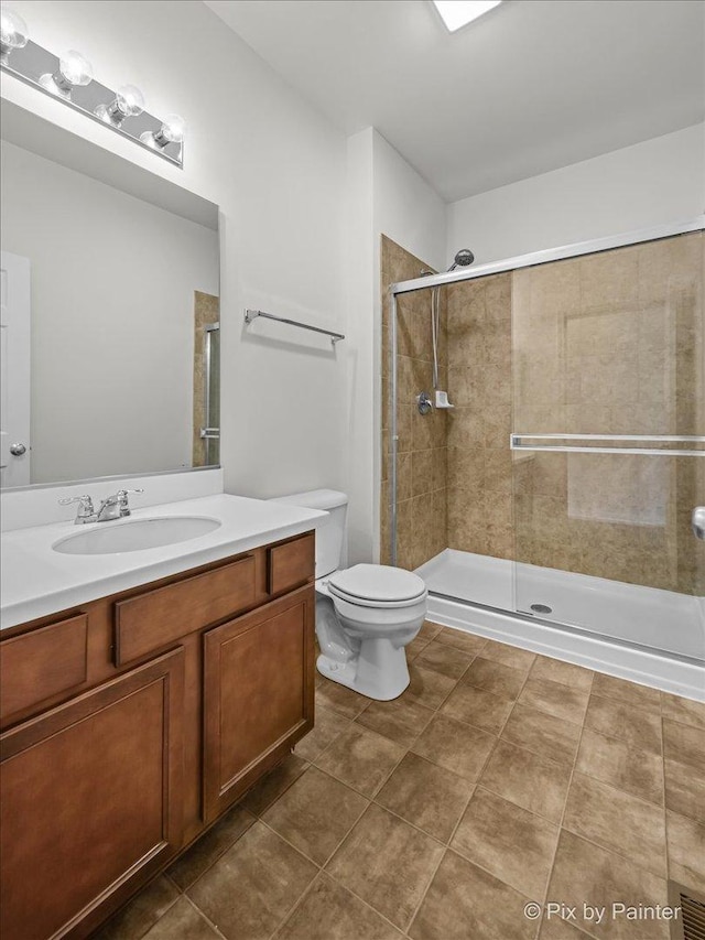 bathroom with tile patterned floors, vanity, toilet, and a shower with door