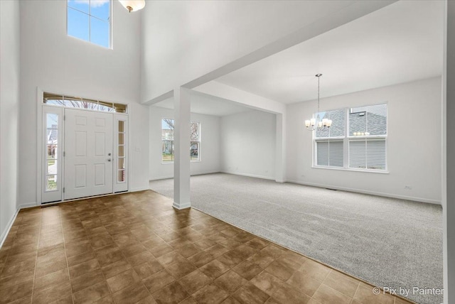 carpeted entryway featuring a high ceiling and a chandelier