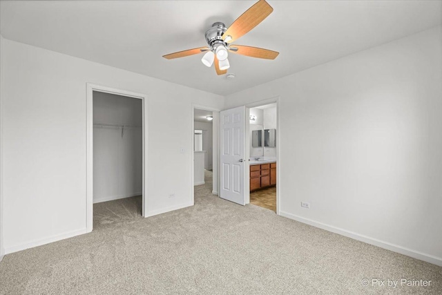 unfurnished bedroom with ensuite bath, ceiling fan, a spacious closet, light colored carpet, and a closet