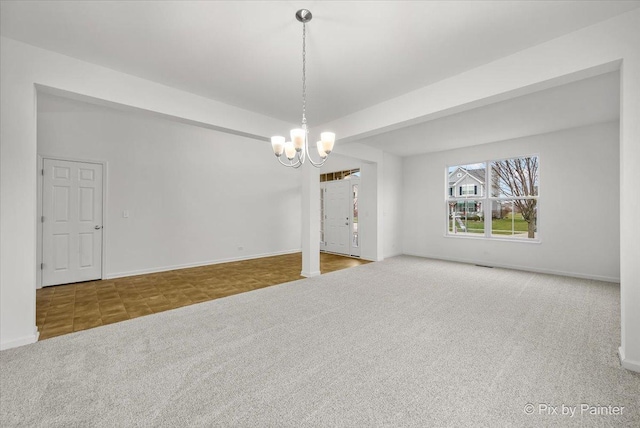 spare room featuring carpet flooring, ornate columns, and an inviting chandelier