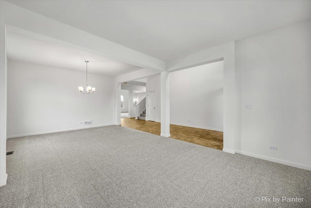 carpeted spare room with a chandelier