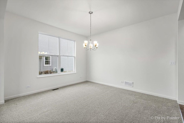 carpeted spare room featuring a chandelier