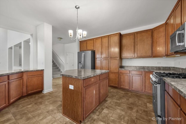 kitchen with stainless steel appliances, dark stone countertops, a chandelier, a center island, and hanging light fixtures