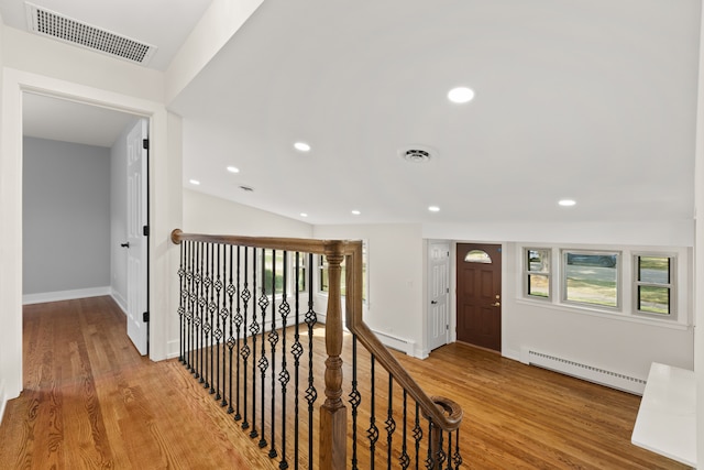 hallway with hardwood / wood-style floors, vaulted ceiling, and a baseboard radiator