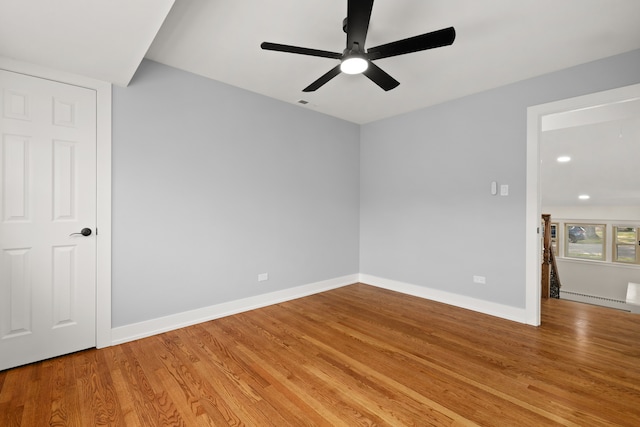 unfurnished room featuring ceiling fan, a baseboard heating unit, and light wood-type flooring