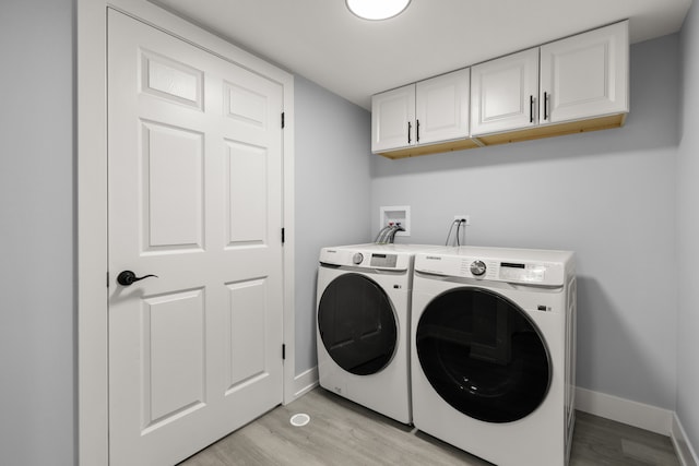 laundry area featuring cabinets, light hardwood / wood-style flooring, and washer and clothes dryer