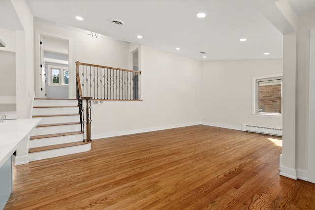 interior space featuring hardwood / wood-style flooring, vaulted ceiling, a wealth of natural light, and a baseboard heating unit