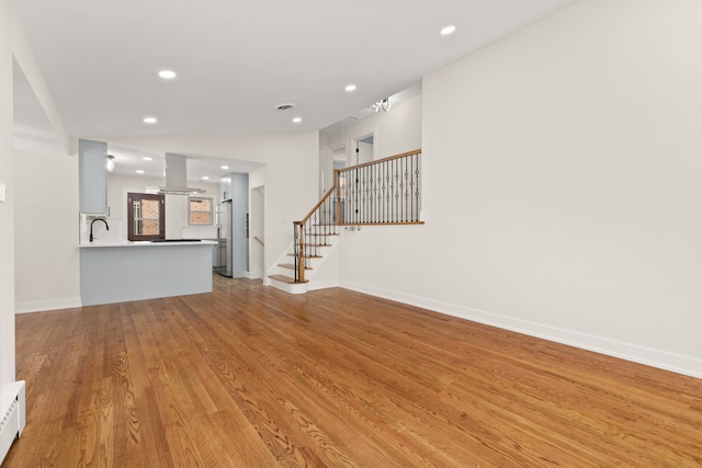 unfurnished living room with light hardwood / wood-style flooring and sink