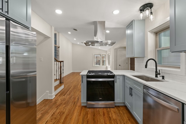 kitchen with sink, island exhaust hood, gray cabinetry, and stainless steel appliances