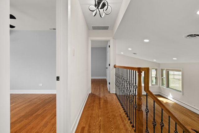 corridor featuring light hardwood / wood-style flooring, a chandelier, and lofted ceiling