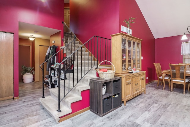 stairway with wood-type flooring and high vaulted ceiling