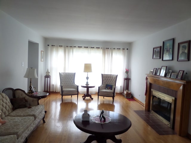 living room featuring a brick fireplace and light wood-type flooring