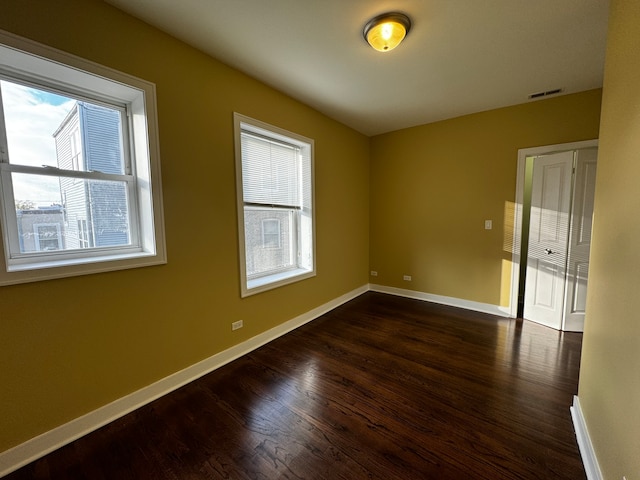 spare room with plenty of natural light and dark wood-type flooring