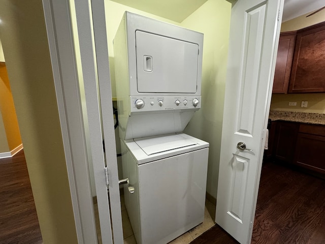 laundry area featuring stacked washer / drying machine and dark wood-type flooring