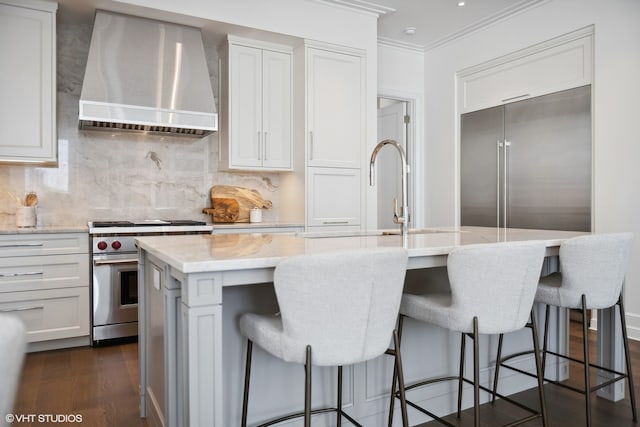 kitchen featuring dark hardwood / wood-style flooring, an island with sink, high quality appliances, and custom exhaust hood