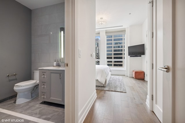 bathroom featuring hardwood / wood-style flooring, vanity, toilet, and tile walls