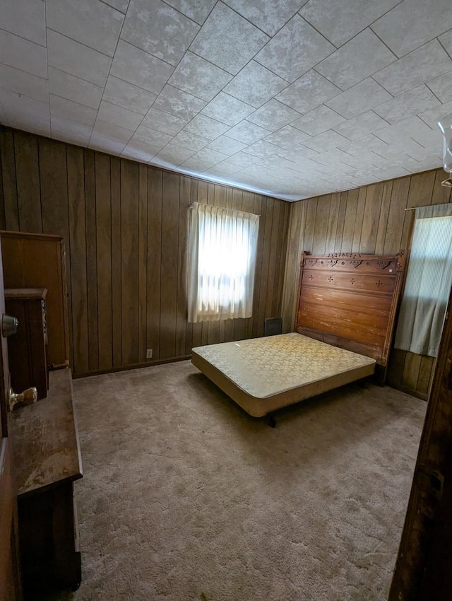 unfurnished bedroom featuring wooden walls and carpet