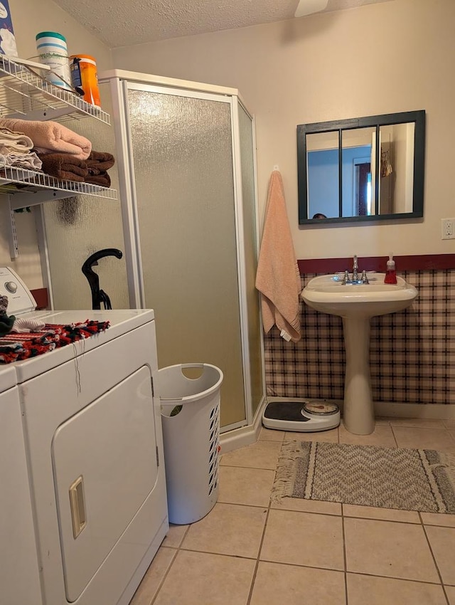 bathroom with tile patterned flooring, washer / dryer, a textured ceiling, and walk in shower