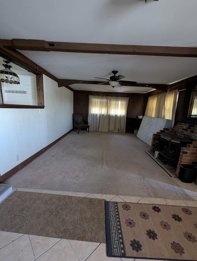 unfurnished living room with a wood stove, beam ceiling, and light colored carpet