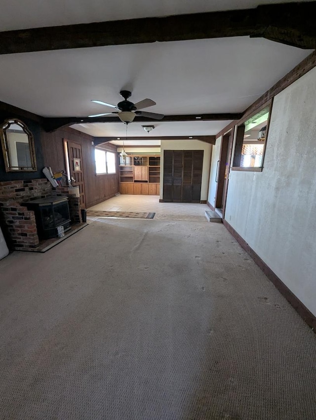 unfurnished living room with light colored carpet, beam ceiling, baseboards, and ceiling fan