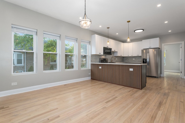 kitchen featuring white cabinetry, light wood-type flooring, decorative light fixtures, and appliances with stainless steel finishes