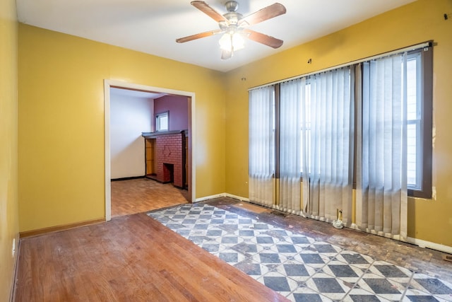 empty room featuring a fireplace, ceiling fan, hardwood / wood-style floors, and a healthy amount of sunlight