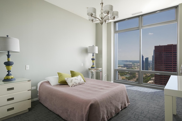 bedroom featuring visible vents, dark carpet, an inviting chandelier, a view of city, and floor to ceiling windows