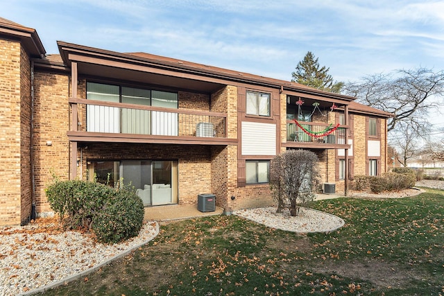 back of property with a yard, a balcony, and central AC unit