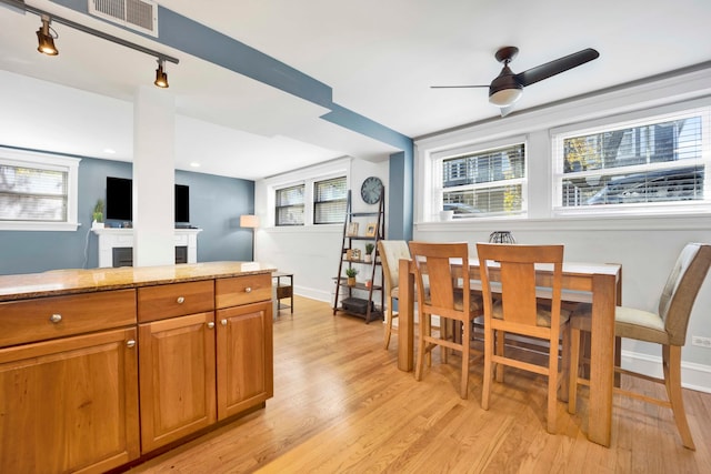 kitchen with light hardwood / wood-style floors, light stone counters, and ceiling fan