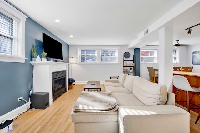 living room featuring plenty of natural light, ceiling fan, and light hardwood / wood-style flooring