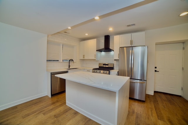 kitchen featuring sink, a center island, wall chimney exhaust hood, and appliances with stainless steel finishes