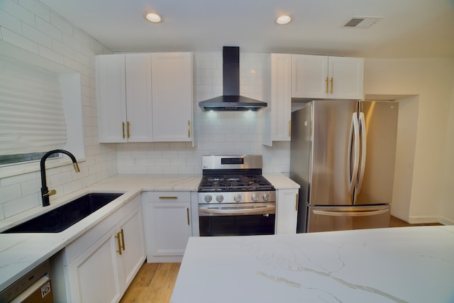 kitchen with white cabinets, wall chimney exhaust hood, sink, and stainless steel appliances