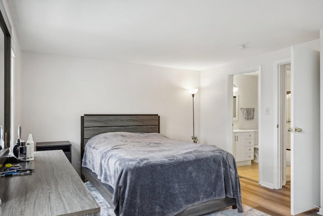 bedroom with connected bathroom and light hardwood / wood-style flooring